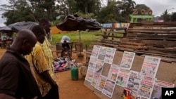 2015年10月26日科特迪瓦，人们在阿比让动物园入口处阅读最近选举的报纸新闻。