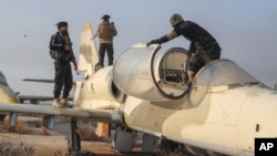 Syrian opposition fighters stand on an aircraft at the Al-Nayrab military airport after they took control of the facility in the outskirts of Aleppo, Syria, Dec. 2, 2024.