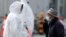 Workers in protective gear escort disembarking passengers from the coronavirus-hit Diamond Princess cruise ship docked at Yokohama Port, south of Tokyo, Feb. 20, 2020.