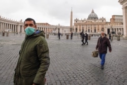 A man wearing a mask walks in St. Peter's Square at the Vatican, March 6, 2020.