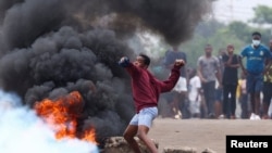 Um manifestante atira uma pedra durante uma greve nacional convocada pelo candidato presidencial Venâncio Mondlane para protestar contra os resultados provisórios das eleições de 9 de outubro, em Maputo, Moçambique, 21 de outubro de 2024