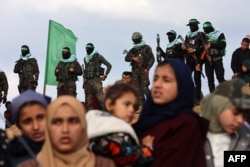 Palestinian Hamas militants and people gather at the site of the handing over of the bodies of four Israeli hostages in Khan Yunis in the southern Gaza Strip on Feb. 20, 2025.