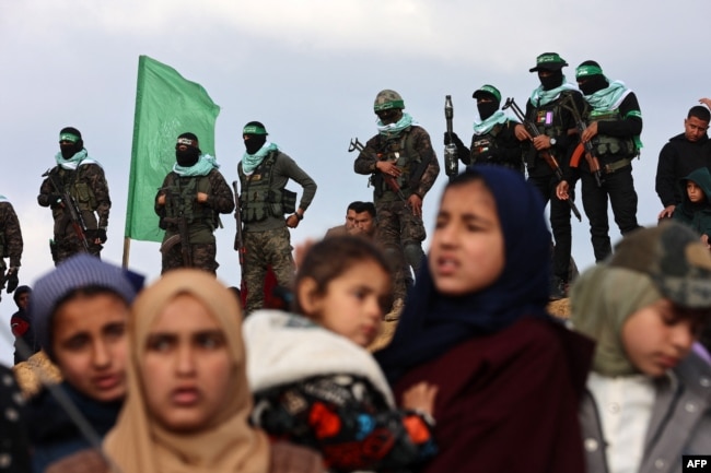 Palestinian Hamas militants and people gather at the site of the handing over of the bodies of four Israeli hostages in Khan Yunis in the southern Gaza Strip on Feb. 20, 2025.