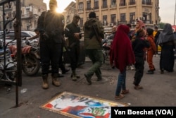 A picture of fallen dictator Bashar al-Assad is displayed on a sidewalk in Damascus, Syria, with residents stepping over it to show their anger against the regime, while HTS soldiers look on, Dec. 12, 2024.