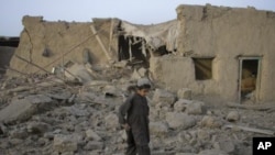 A boy walks past a mud house damaged by a bomb explosion early morning in the Pakistan-Afghanistan border town of Chaman, July 14, 2011