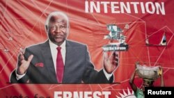 A child street vendor stands in front of a poster for Sierra Leone's ruling party presidential candidate Ernest Bai Koroma, Freetown, Nov. 16, 2012.