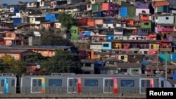 A metro train moves past a cluster of houses at the Asalpha slum in Mumbai, India, April 12, 2018. 