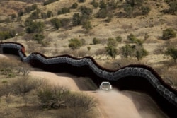 FILE - A Customs and Border Control agent patrols on the U.S. side of a razor-wire-covered border wall along Mexico east of Nogales, Ariz., March 2, 2019.