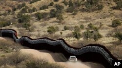 FILE - A Customs and Border Control agent patrols on the U.S. side of a razor-wire-covered border wall along Mexico east of Nogales, Ariz., March 2, 2019.