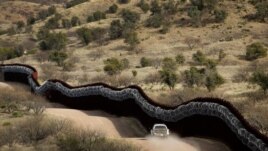 FILE - A Customs and Border Control agent patrols on the U.S. side of a razor-wire-covered border wall along Mexico east of Nogales, Ariz., March 2, 2019.