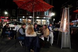 Diners have dinner outdoors, Nov. 6, 2020, in Boston's North End. More stringent coronavirus restrictions are now in effect in Massachusetts, including requiring restaurants to stop providing table service at 9:30 p.m.