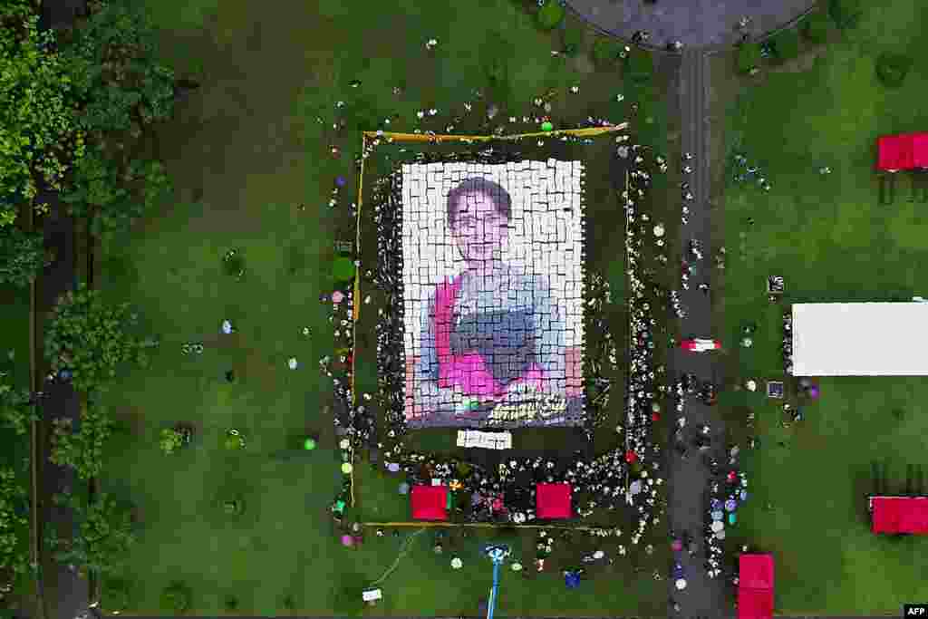 This aerial picture taken and provided, June 19, 2019 by one of the event organizers, Tharr Zaw, shows supporters making a mosaic portrait of Myanmar State Counsellor Aung San Suu Kyi with placards during an event to celebrate her 74th birthday in Yangon.