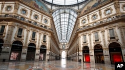 FILE - In this March 22, 2020 photo, a man walks in an empty Vittorio Emanuele II gallery shopping arcade in downtown Milan, Italy.