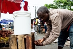 FILE - A man washes his hands with chlorinated water at the Mabibo market in Dar es Salaam, Tanzania, April 16, 2020.