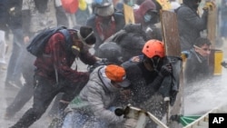 Los manifestantes antigubernamentales se protegen de un cañón de agua de la policía durante los enfrentamientos en Madrid, en las afueras de Bogotá, el viernes 28 de mayo de 2021.