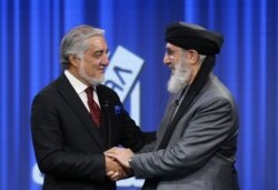 FILE - Afghan presidential candidates Abdullah Abdullah and former Afghan warlord Gulbuddin Hekmatyar shake hands before the presidential election debate at TOLO TV studio in Kabul, Afghanistan Sept. 25, 2019.