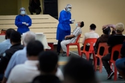 A medical worker collects a swab sample from a man during coronavirus testing in Petaling Jaya, Malaysia, Jan. 18, 2021.