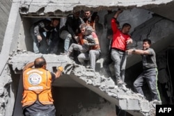 Anggota pertahanan sipil Palestina menyelamatakan seorang anak di rumah keluarga Muqat berlantai empat di Zarqa, utara Kota Gaza, 26 Oktober 2024. (Foto: AFP)