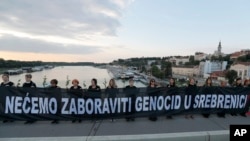 Anggota organisasi anti-perang "Women in Black", memegang spanduk bertuliskan: "Kami tidak akan melupakan genosida di Srebrenica!" sebagai bagian dari pertemuan untuk memperingati 24 tahun tragedi Srebrenica, di Beograd, Serbia, Rabu, 10 Juli 2019. (Foto: AP/Darko Vojinovic)