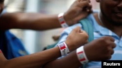 Migrants from Honduras, part of a new caravan from Central America trying to reach the United States, show their bracelets in an immigration facility in Ciudad Hidalgo, Mexico, Jan. 17, 2019.