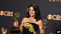 FILE - Julia Louis-Dreyfus poses in the press room with her awards for outstanding lead actress in a comedy series and outstanding comedy series for "Veep" at the 69th Primetime Emmy Awards, Sept. 17, 2017, at the Microsoft Theater in Los Angeles.