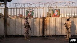 Des agents militaires dominicains montent la garde près de la porte du pont sur la rivière Massacre avant de permettre aux Haïtiens d'entrer à Dajabon, en République dominicaine, depuis Ouanaminthe, en Haïti, à la frontière nord entre les pays, le 5 mars 