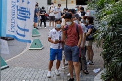 People wearing face masks queue up to vote in Hong Kong, July 11, 2020, in an unofficial "primary" for pro-democracy candidates ahead of legislative elections in September.