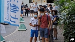 People wearing face masks queue up to vote in Hong Kong, July 11, 2020, in an unofficial "primary" for pro-democracy candidates ahead of legislative elections in September.