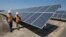 FILE - Employees walk past solar panels at a plant in Dixon, California, Aug. 17, 2017.