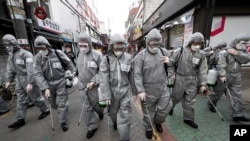 Army soldiers wearing protective suits spray disinfectant as a precaution against the new coronavirus at a shopping street in Seoul, South Korea, March 4, 2020. 