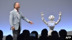 FILE - Softbank Group's Masayoshi Son and humanoid robot Pepper deliver a presentation at the Softbank World 2015 in Tokyo, July 30, 2015. 