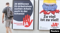 A man walks past posters of the Swiss People's Party (SVP) and of the Komitee Arbeitsplaetze fuer Einheimische schuetzen (committee to protect jobs for locals) against the anti-immigration initiative in Zurich, Switzerland, Sept. 17, 2020.