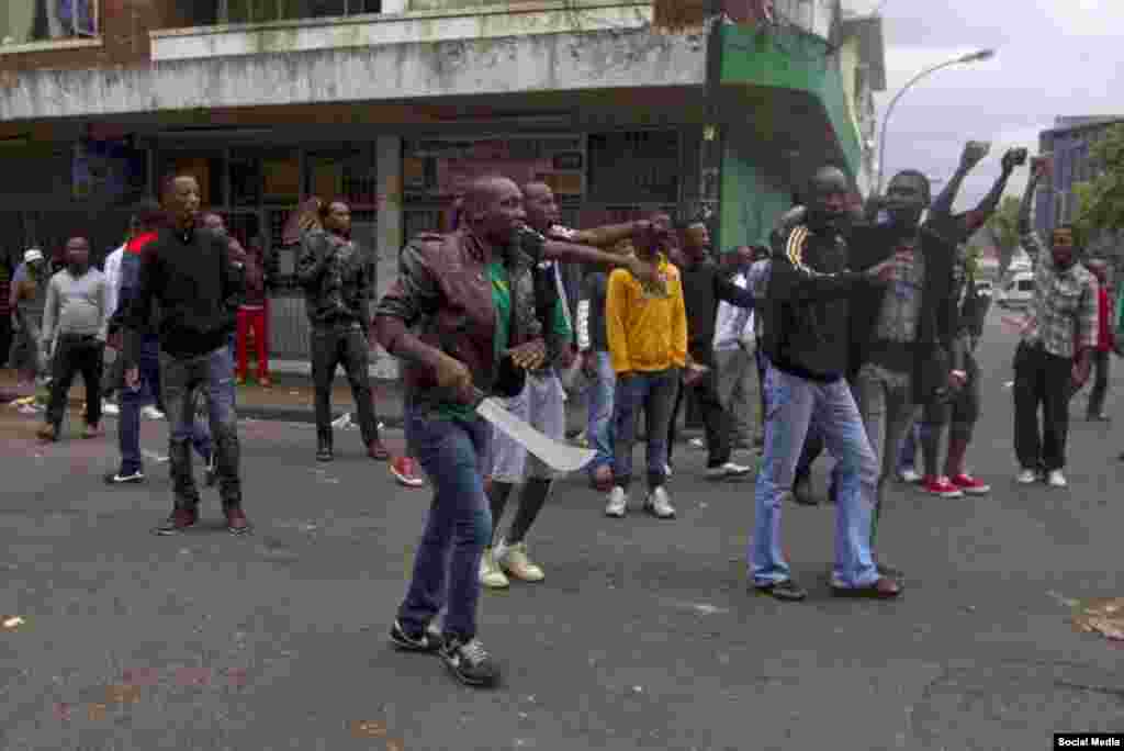 Pessoas seguem pela rua com facas, entre outras armas.