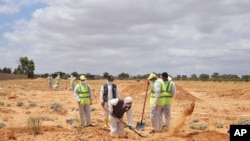 Libyan Ministry of justice employees dig out at a siyte of a suspected mass grave in the town of Tarhouna, Libya, June 23, 2020.