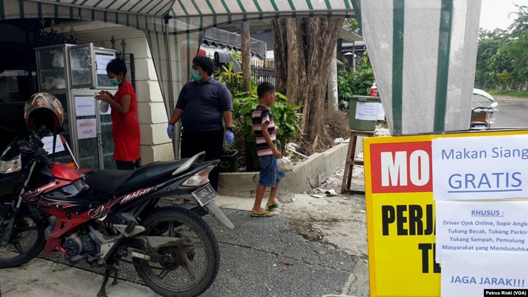 Masyarakat miskin yang membutuhkan makan siang diperbolehkan mengambil nasi bungkus dan vitamin C yang telah disediakan. (Foto: VOA/Petrus Riski)