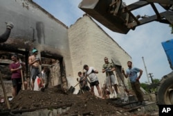 Young volunteers clear debris from a building destroyed by a Russian rocket while enjoying a techno performance by a DJ in the village of Yahidne, Chernihiv Region, Ukraine, Sunday, July 24, 2022.