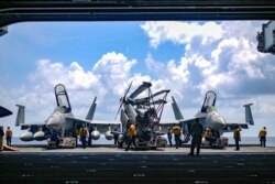 FILE - U.S. Navy sailors move aircraft from an elevator into the hangar bay of aircraft carrier USS Theodore Roosevelt in South China Sea, Apr. 8, 2018. (US Navy/Mass Communication Specialist Seaman Michael Hogan/Handout via Reuters)