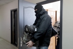 A policeman leaves the BAJ office after a raid in Minsk, on Feb. 16, 2021. Police in Belarus also raided the homes and offices of 25 journalists, rights defenders and trade union members.