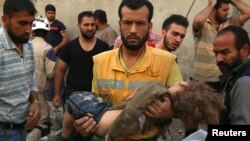 A medic carries the body of a child after airstrikes in the rebel-held Karam Houmid neighborhood in Aleppo, Syria, Oct. 4, 2016.