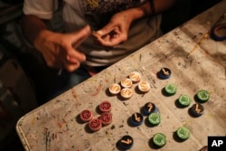 FILE - Dana Lopez sands a wooden token for poleana, a board game invented in prison, in his workshop in Mexico State, Mexico, Oct. 25, 2024.