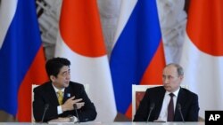 Presiden Rusia Vladimir Putin mendengarkan keterangan PM Jepang Shinzo Abe (kiri) dalam konferensi pers saat berada di Kremlin, Moskow untuk kunjungan kenegaraaan (29/4).