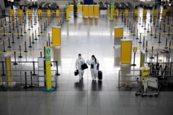 Passengers wearing hazmat suits for protection against COVID-19 walk through the Ninoy Aquino International Airport in Paranaque, Metro Manila, Philippines.