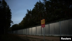 资料照片：在波兰的奥帕卡·杜扎村，夕阳映照着波兰-白俄罗斯边界围栏。