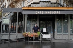 A street vendor waits for customers to sell her flowers in front of the closed Daguerre Cafe on Rue Daguerre in Paris, May 22, 2020.