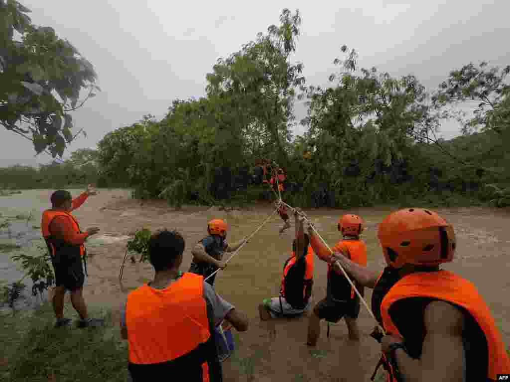 Rescuers evacuate residents from their homes near a swollen river due to heavy rains brought about by Tropical Storm Kompasu in Gonzaga town, Cagayan province, north of Manila, in this photo taken October 11, 2021, and received October 12 from Gonzaga Municipal Disaster Risk Reduction and Management Office.