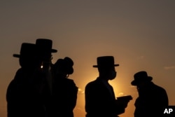FILE - Ultra-Orthodox Jews of the Kiryat Sanz Hassidic sect pray on a hill overlooking the Mediterranean Sea as they participate in a Tashlich ceremony in Netanya, Israel, Sept. 24, 2020.