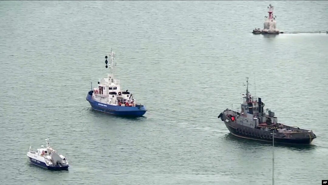Sebuah kapal Ukraina yang disita (kanan), ditarik oleh kapal penjaga pantai Rusia keluar dari pelabuhan di Kerch, Crimea, Minggu, 17 November 2019. (Krym 24 tv station via AP Television)