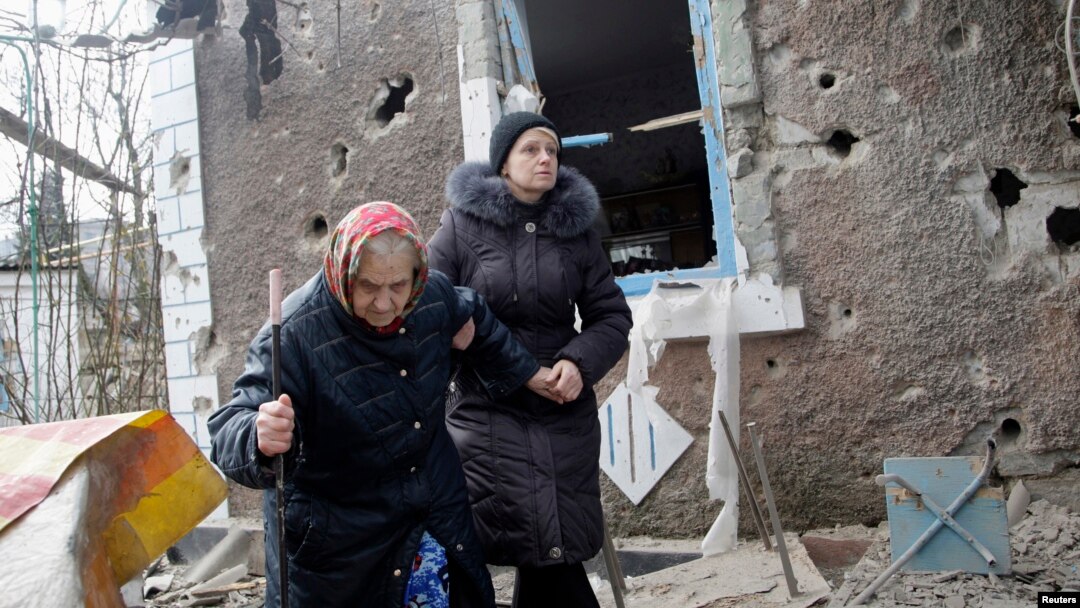 Cư dân đi bộ bên ngoài một ngôi nhà bị hư hại bởi pháo kích ở Donetsk, miền đông Ukraine, ngày 3/2/2015.