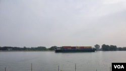 A container ship moves goods along the Saigon River. Vietnam has lifted rice export controls, easing fears of food shortages. (VOA News)
