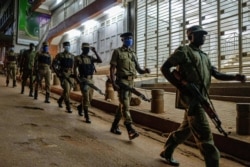 FILE - Ugandan police officers and members of Local Defence Units, a paramilitary force composed of civilians, patrol during the coronavirus lockdown after the 7 p.m. curfew in Kampala, Uganda, April, 29, 2020.